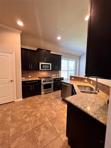 a kitchen with stainless steel appliances granite countertop a sink counter space cabinets and a large window