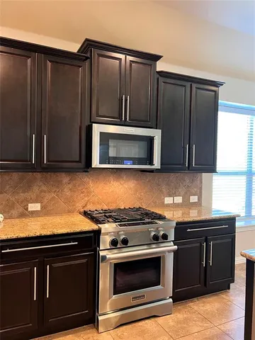a kitchen with granite countertop a stove and a microwave with cabinets