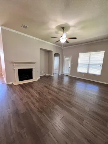 a view of an empty room with wooden floor fireplace and a window