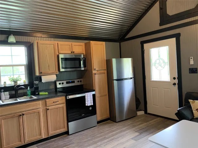 a kitchen with stainless steel appliances granite countertop a refrigerator a stove a sink dishwasher and wooden floor