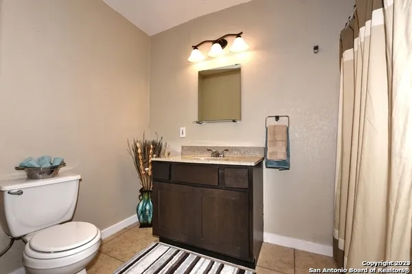 a bathroom with a granite countertop toilet sink and mirror