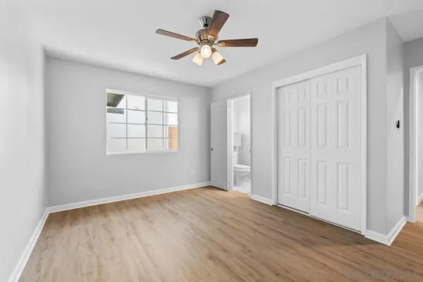 a view of an empty room with wooden floor and closet