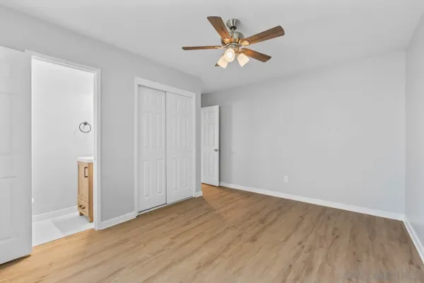 a view of empty room with wooden floor and fan