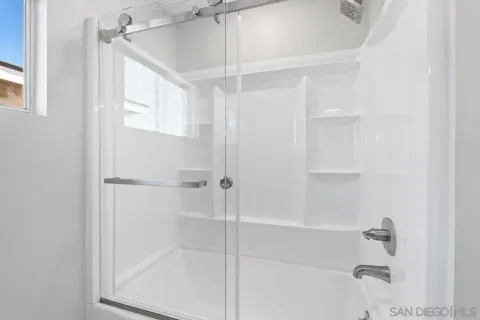 a view of an empty room with wooden floor and window