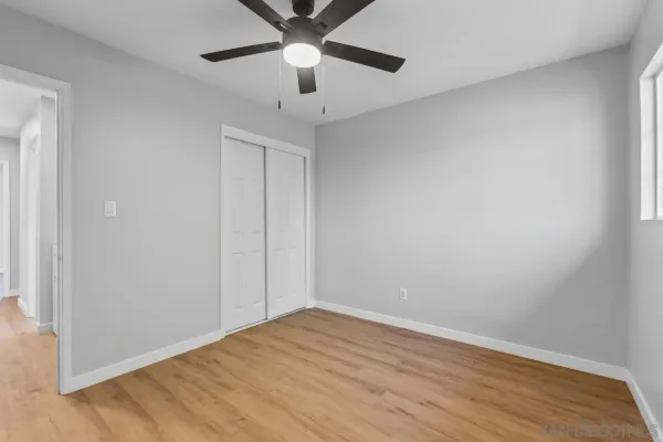 a view of an empty room with wooden floor & closet