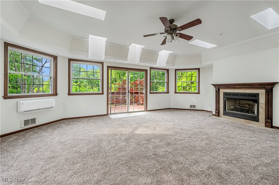 12358 Harmon Road New Springfield, OH 44443 - Photo 14 of 44 Unfurnished living room with a skylight, a raised ceiling, carpet flooring, a tile fireplace, and a ceiling fan