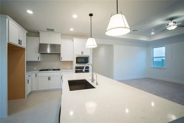a kitchen with stainless steel appliances a stove and a white cabinet