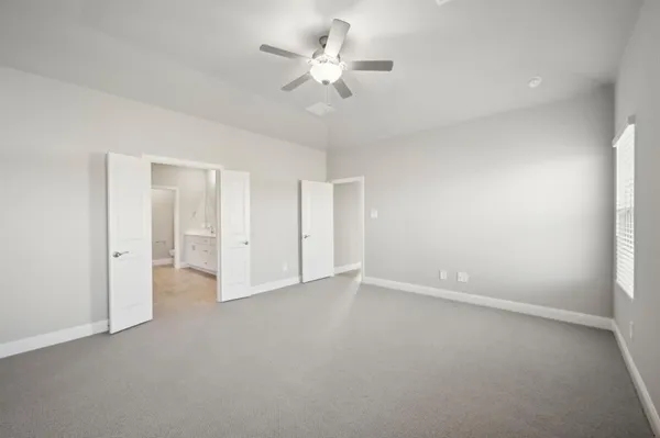 an empty room with chandelier fan and closet area