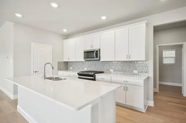 a kitchen with stainless steel appliances granite countertop a sink dishwasher a stove and a refrigerator with wooden floor