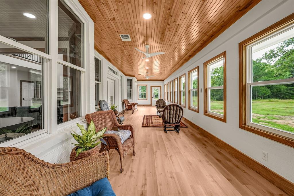 1037 Harrison Road Denison, TX 75021 - Photo 19 of 39 Spacious sunroom featuring a natural wood plank ceiling, light wood-finish flooring, white walls, and a series of large windows with natural wood trim