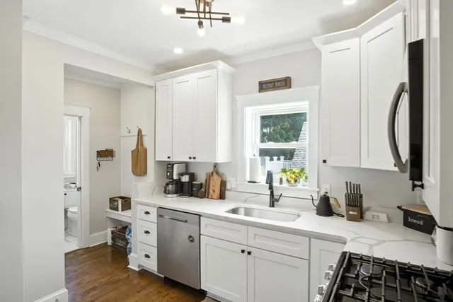 a kitchen with stainless steel appliances a sink cabinets and wooden floor