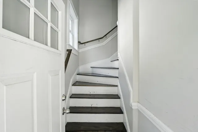 a view of staircase with wooden floor and white walls