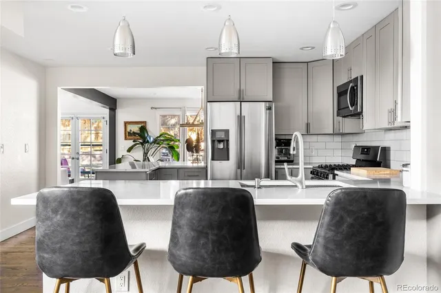 a kitchen with stainless steel appliances granite countertop a refrigerator a stove a sink dishwasher a dining table and chairs with wooden floor