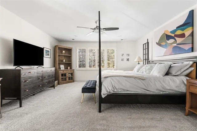 a spacious bedroom with a bed and a flat tv screen on dresser