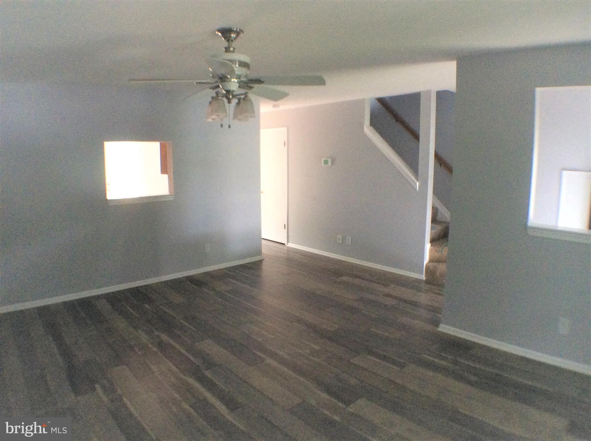 2021 Putnam Road Baltimore, MD 21227 - Photo 5 of 18 an empty room with wooden floor chandelier fan and windows