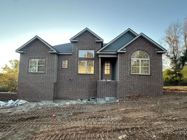a view of a brick house with yard and large tree