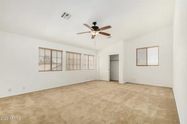 an empty room with chandelier fan and closet