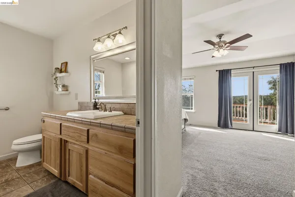 a en suite bathroom with a granite countertop sink toilet and a mirror