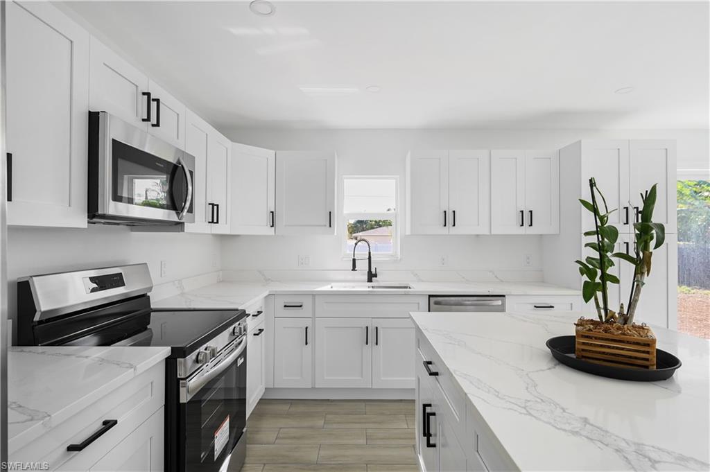 a kitchen with stainless steel appliances a sink a stove a microwave and cabinets