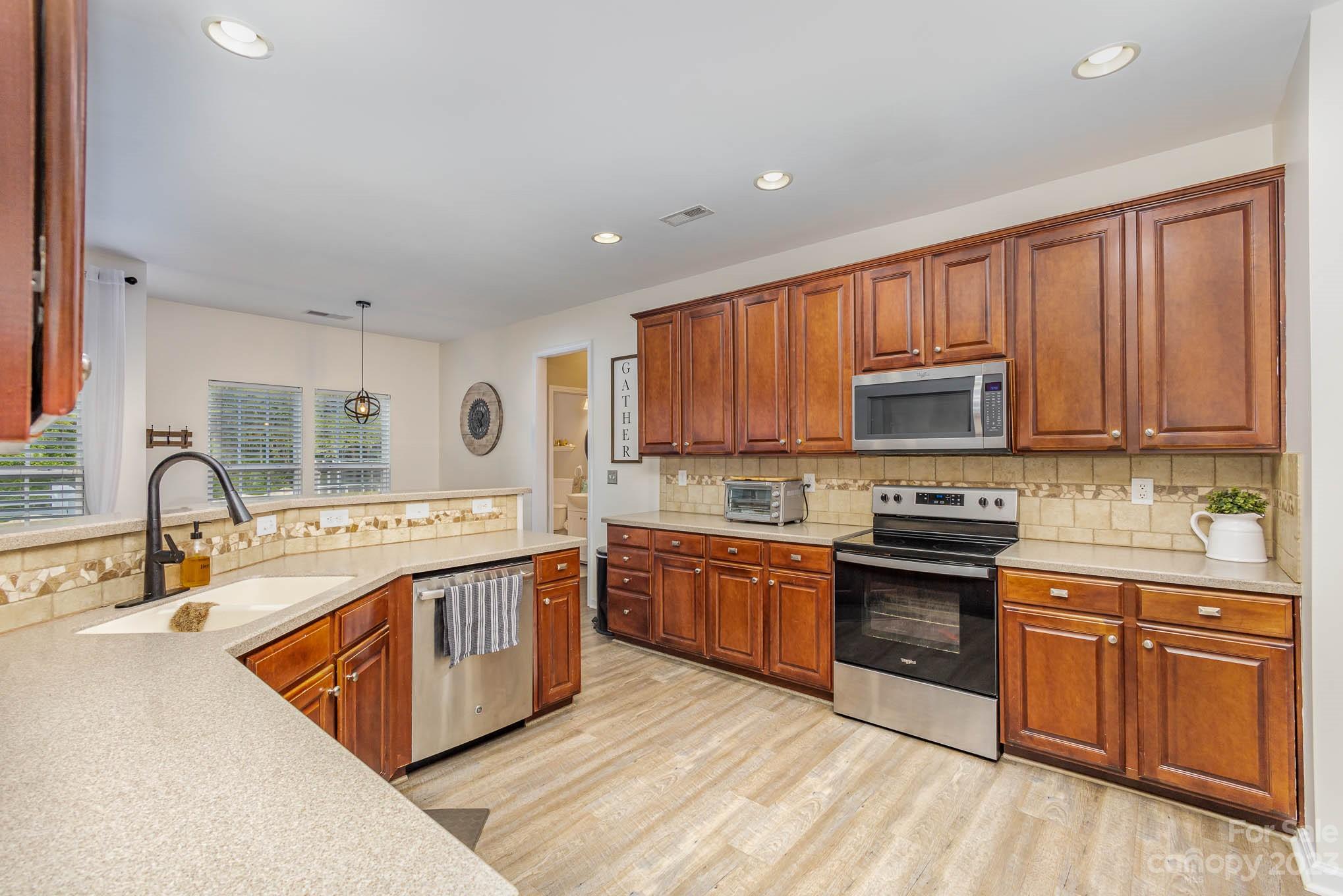 2379 Smith Cove Road Denver, NC 28037 - Photo 11 of 40 a large kitchen with stainless steel appliances granite countertop a stove top oven a sink dishwasher and white cabinets with wooden floor