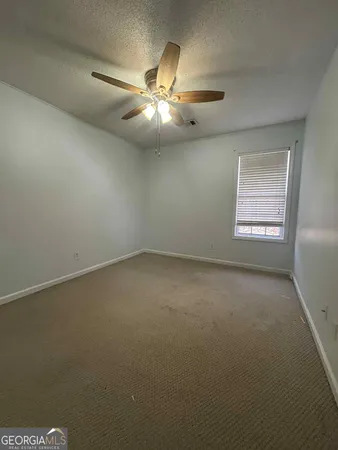an empty room with a window and a fan