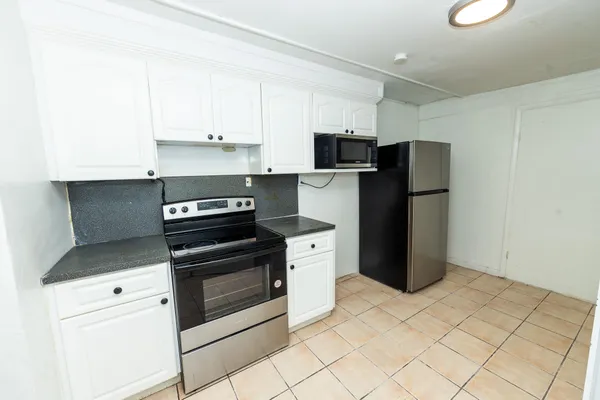 a kitchen with stainless steel appliances a refrigerator stove and white cabinets