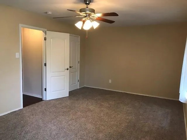 an empty room with closet and a ceiling fan