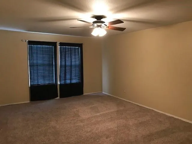 a view of an empty room with a ceiling fan and window
