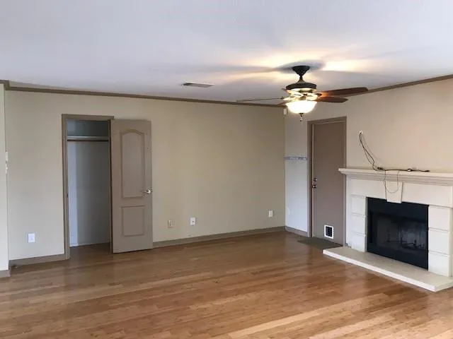 a view of a livingroom with a fireplace a ceiling fan and wooden floor