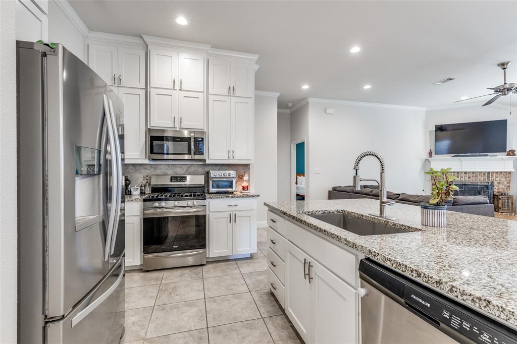 1173 Roping Reins Way Fort Worth, TX 76052 - Photo 24 of 24 Kitchen with stainless steel appliances, open floor plan, white cabinets, a fireplace, and recessed lighting