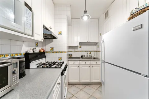 a kitchen with white cabinets and appliances