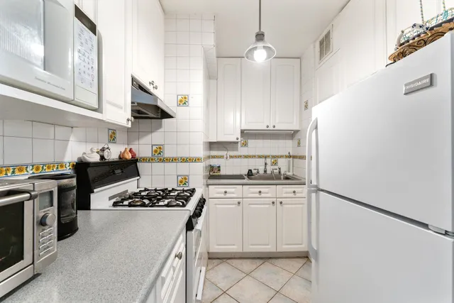 a kitchen with white cabinets and appliances