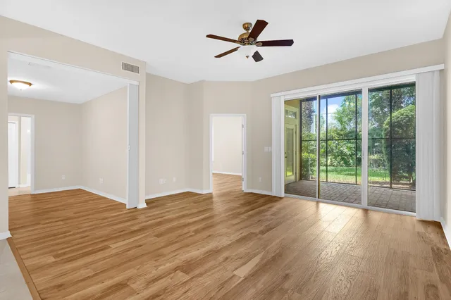 a view of empty room with wooden floor and fan