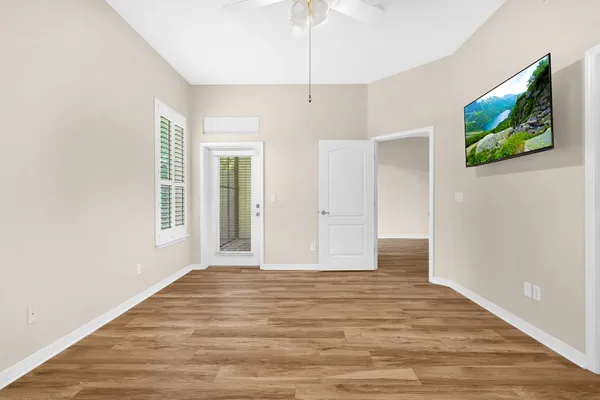 a view of an empty room with window and wooden floor
