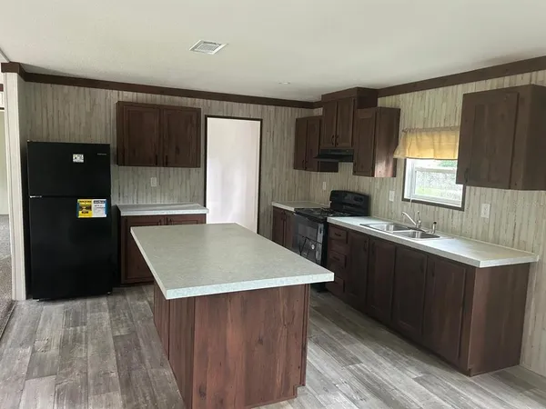 a kitchen with a wooden floor and black cabinets