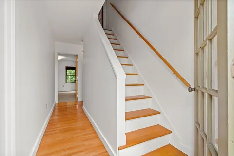 a view of a hallway with wooden floor and stairs