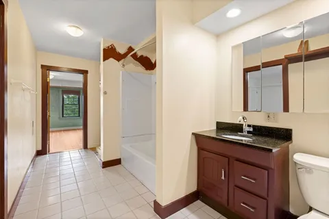 a bathroom with a granite countertop sink a toilet a mirror and shower