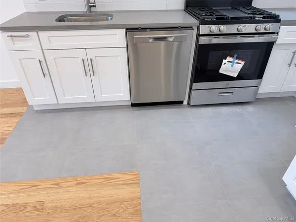 a kitchen with stainless steel appliances granite countertop white cabinets and a stove a oven with white countertops