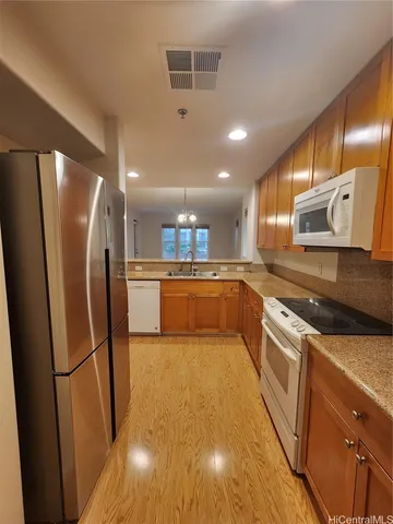 a large kitchen with stainless steel appliances granite countertop a refrigerator a sink a stove and white cabinets with wooden floor