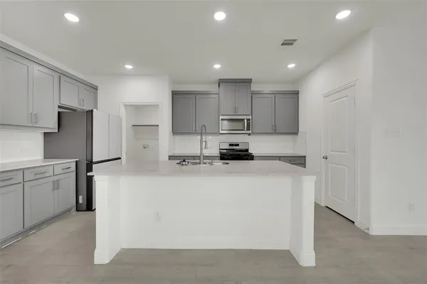 a kitchen with kitchen island a white counter top space cabinets and stainless steel appliances