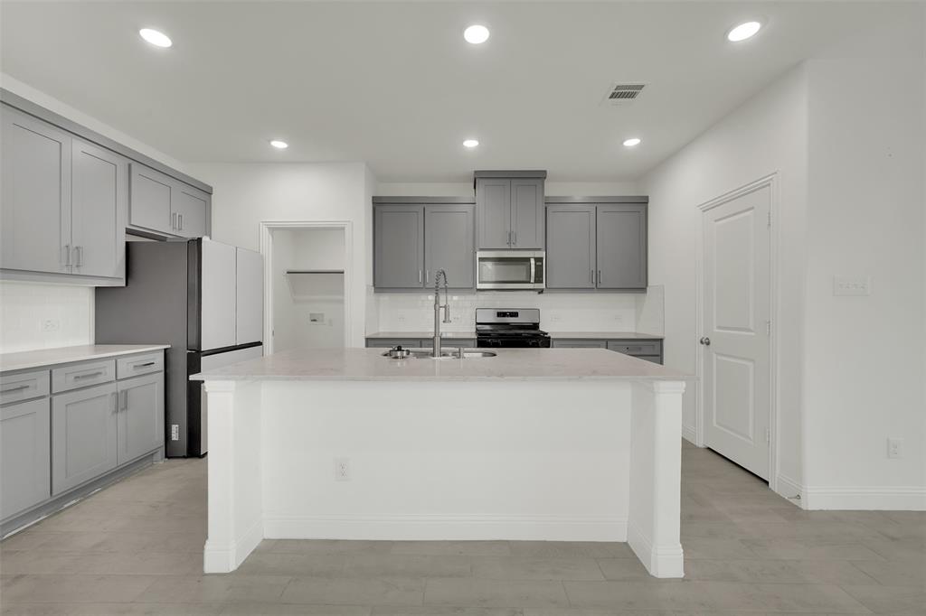 2901 Isla Terrace Princeton, TX 75407 - Photo 8 of 33 a kitchen with kitchen island a white counter top space cabinets and stainless steel appliances