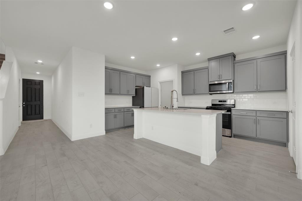 2901 Isla Terrace Princeton, TX 75407 - Photo 9 of 33 a kitchen with stainless steel appliances granite countertop a refrigerator sink and white cabinets
