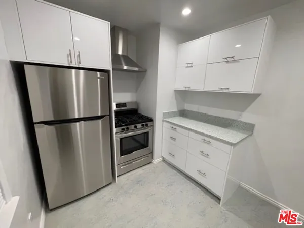 a kitchen with white cabinets and refrigerator