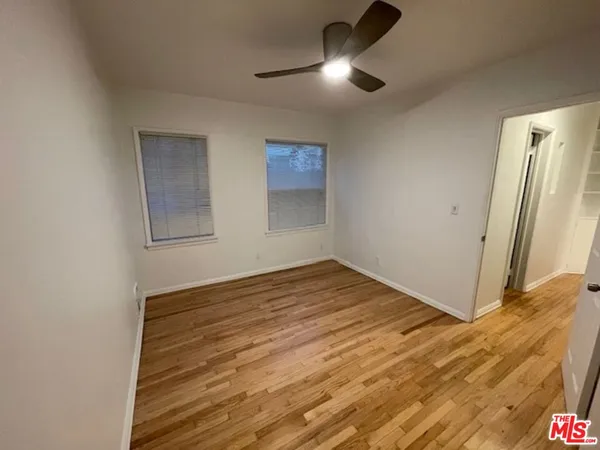 an empty room with wooden floor and natural light
