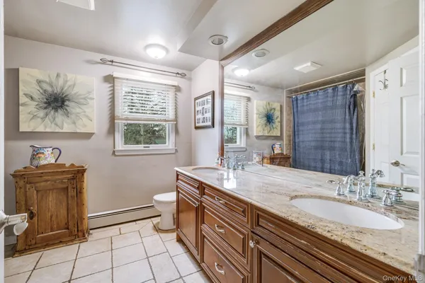 a bathroom with a granite countertop sink a toilet a mirror and a window