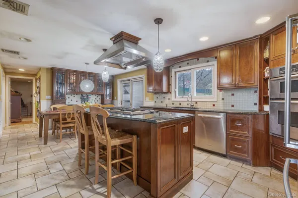 a kitchen with stainless steel appliances granite countertop a stove top oven a sink a dining table and chairs with wooden floor