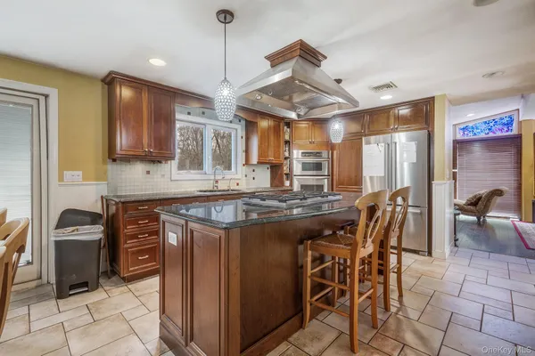 a kitchen with stainless steel appliances granite countertop a stove a refrigerator a sink a dining table and chairs with wooden floor