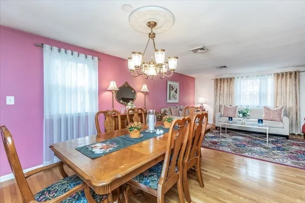 a dining room with furniture a chandelier and wooden floor