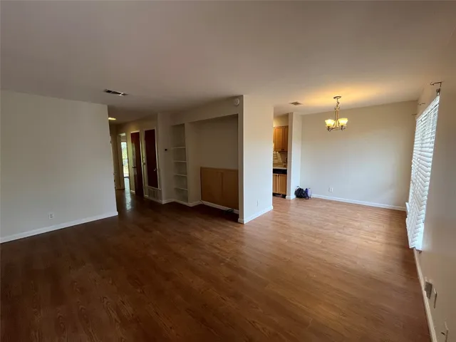 a view of a big room with wooden floor and windows