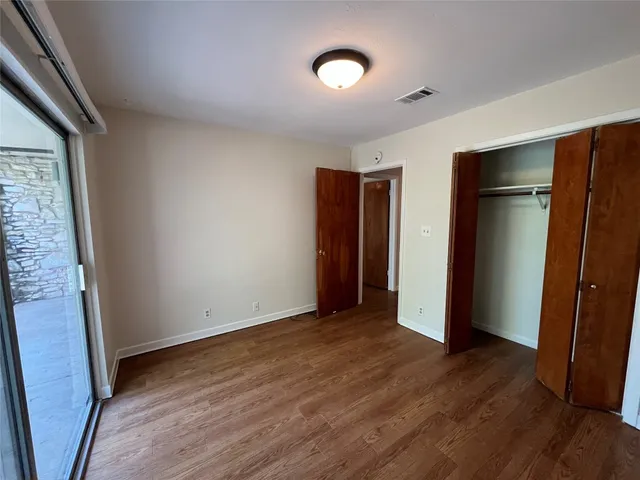 an empty room with wooden floor and closet area